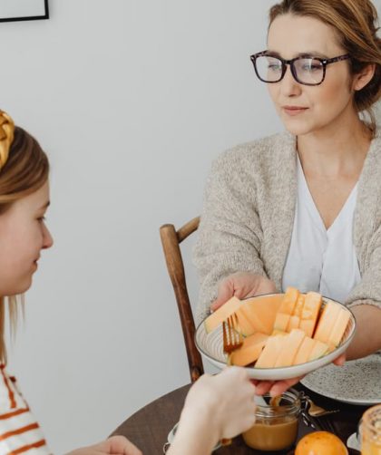 Mother and daughter enjoying a healthy breakfast together with fresh fruits and juice.